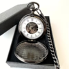 Reloj mecánico oscuro abierto con esfera blanca de números romanos