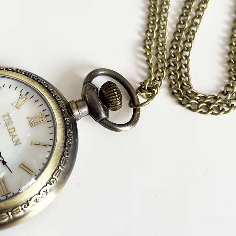 Detalle de la corona, el borde decorado y la cadena del reloj