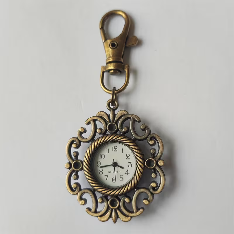 Reloj llavero con marco floral abierto en tono bronce y esfera blanca